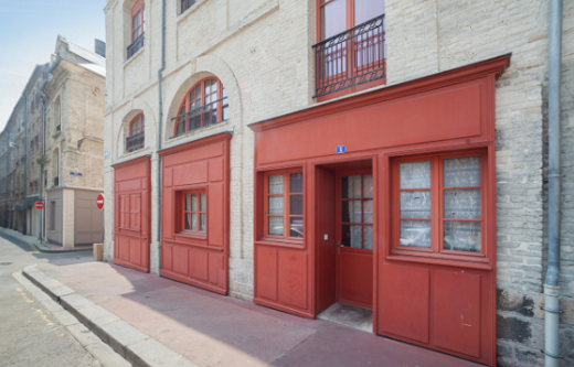 La façade donnant sur la place après réhabilitation: boiseries rouges au rez-de chaussée, briques blanches