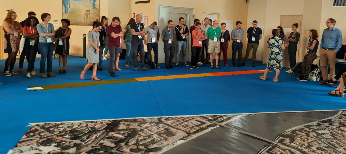 Participants alignés au début du jeu, devant une grande carte de ville