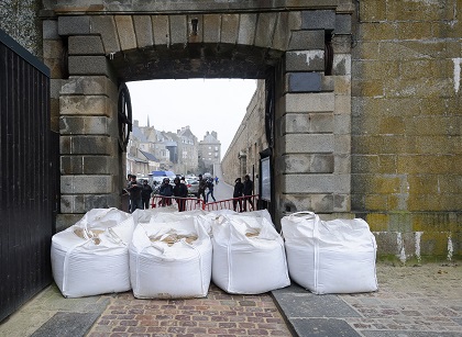 Mesures de prévention contre de hautes marées et un risque de tempête à Saint-Malo, avec des sacs de sable