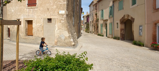 enfant sur un tricycle dans un village rénové du sud