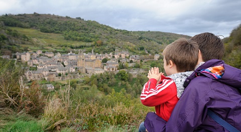 Vue de deux touristes devant le village médiéval de Conques en Aveyron