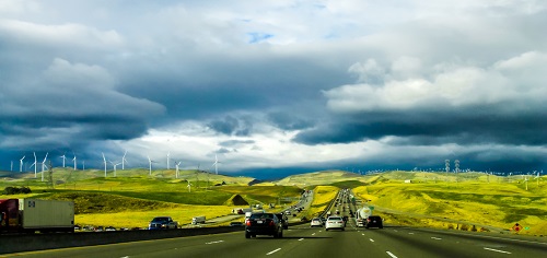véhicules sur une autoroute avec des éoliennes en fond