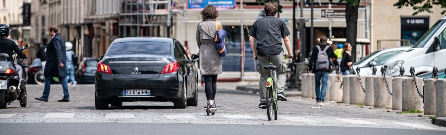 rue à paris avec piéton, vélo, trottinette, voiture