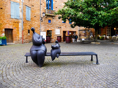 sculptures rondes en forme de personnages sur un banc, sur une place