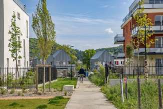 un homme marche sur une allée bordée de petits immeubles