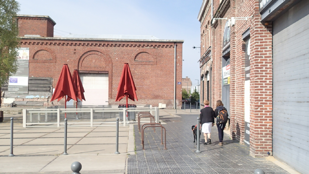 Place principale d'Euratechnologies à Lille, traversée par une personne non-voyante.