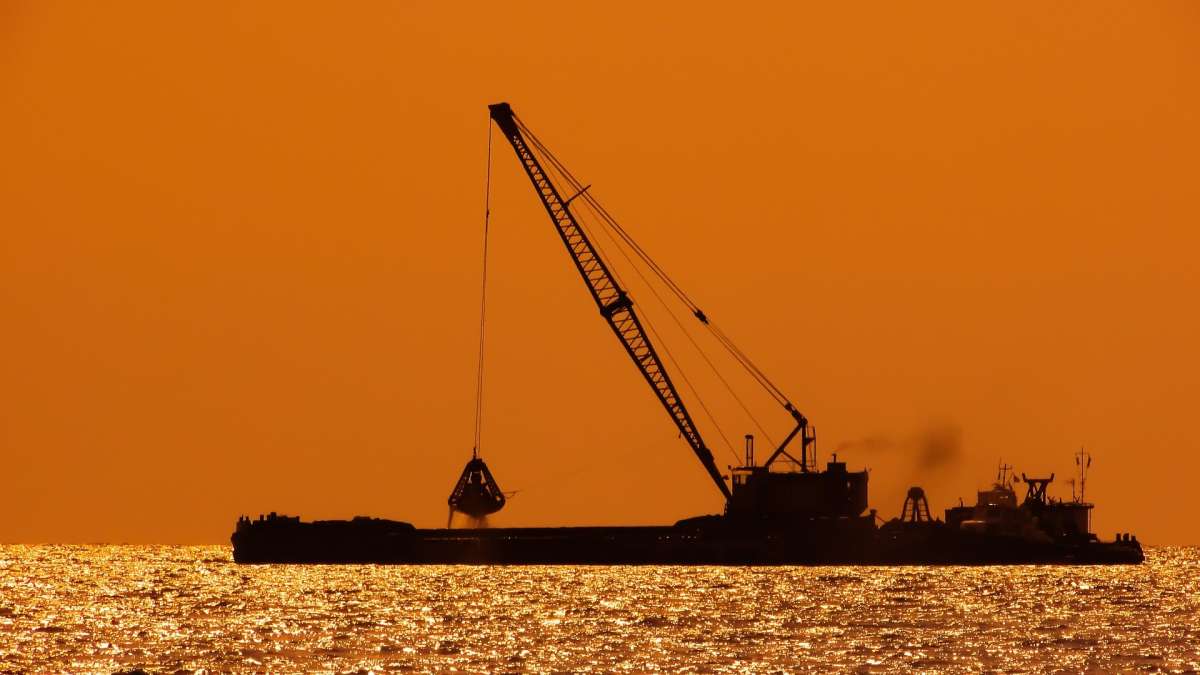 Vue d'un bateau de dragage en mer au coucher de soleil
