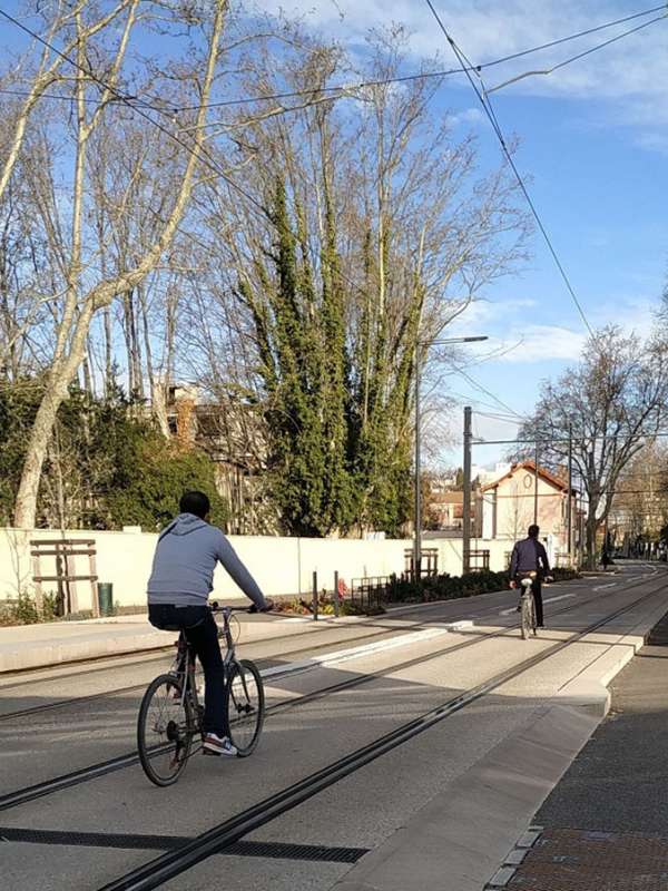 2 personnes à vélo sur une ligne de tramway à Avignon