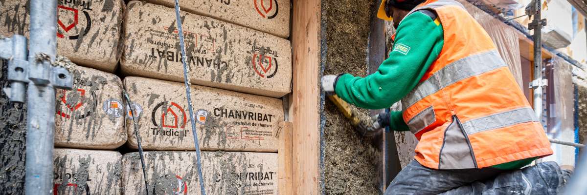 Ouvrier en train de poser une couche de béton de chanvre sur la façade d'un batiment
