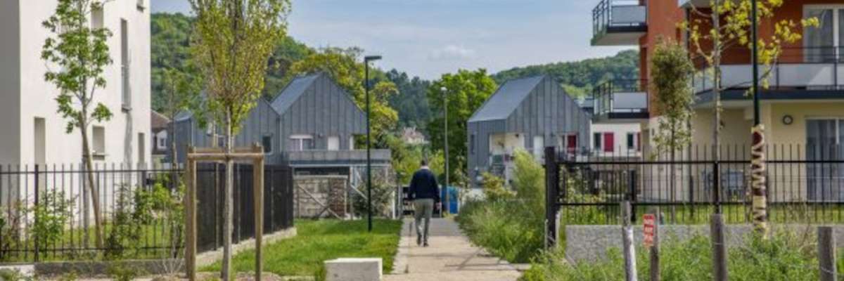 un homme marche sur une allée bordée de petits immeubles